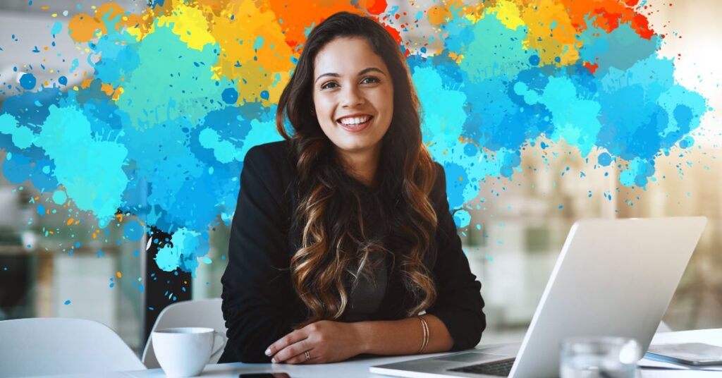 A smiling professional woman sitting at a desk with a laptop, with a vibrant, colorful background representing creativity and career development.